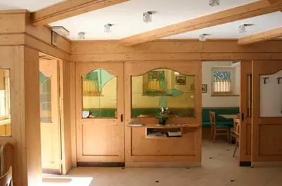 a room with wooden doors and windows and a table at Albergo Hofer in Bolzano