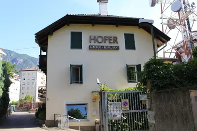 a white building with a sign for a hotel at Albergo Hofer in Bolzano