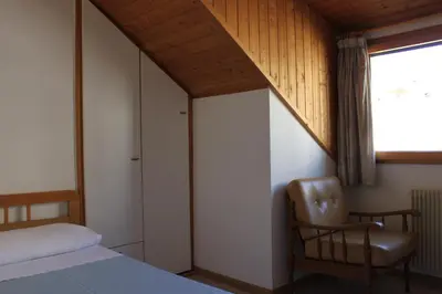 a bedroom with a bed and a chair and a window at Albergo Hofer in Bolzano