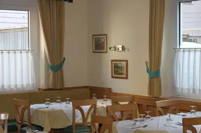a dining room with tables and chairs and windows at Albergo Hofer in Bolzano