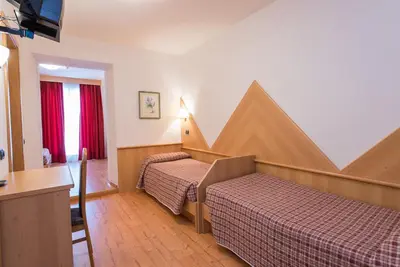 a hotel room with two beds and a table at Hotel Italia in Castello di Fiemme