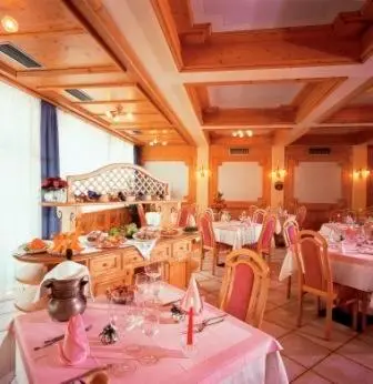 a dining room with tables and chairs with pink table cloth at Hotel Italia in Castello di Fiemme