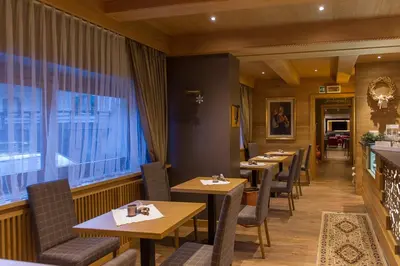 a restaurant with wooden tables and chairs and a window at Hotel Italia in Castello di Fiemme