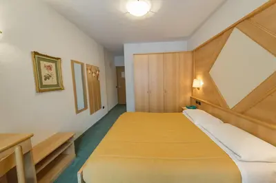 a small bedroom with two beds in a room at Hotel Italia in Castello di Fiemme