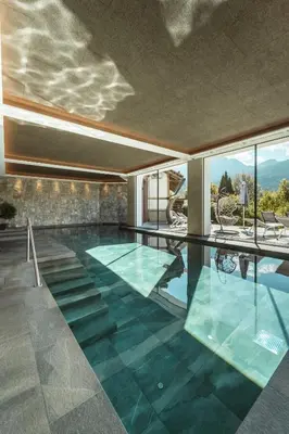 an indoor pool with a view of the mountains from a house at Historic Hotel Alte Goste in Valdaora