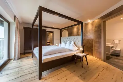 a bedroom with a bed and a large window at Historic Hotel Alte Goste in Valdaora