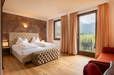 a bedroom with a large bed with a large window at Historic Hotel Alte Goste in Valdaora