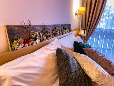 a bedroom with a bed with pillows and a deer on it at Hotel da Beppe Sello in Cortina dʼAmpezzo