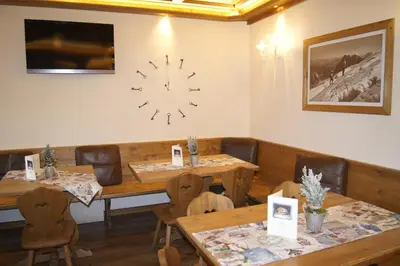 a restaurant with wooden tables and chairs and a clock on the wall at Hotel da Beppe Sello in Cortina dʼAmpezzo
