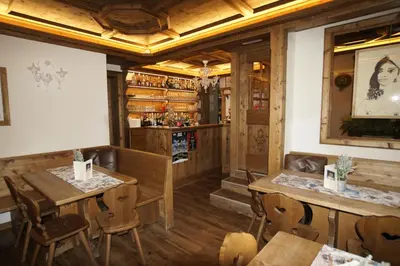 a restaurant with wooden tables and chairs and a bar at Hotel da Beppe Sello in Cortina dʼAmpezzo