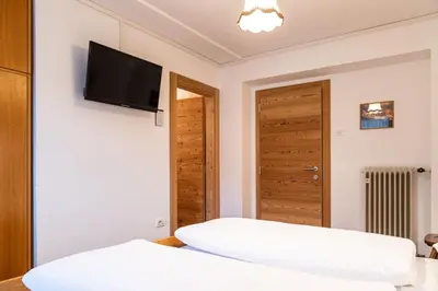 a bedroom with two beds and a flat screen tv on the wall at Garni Juri in La Villa