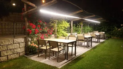 a row of tables and chairs in a garden at night at La Montanina Hotel in Val di Non in Malosco
