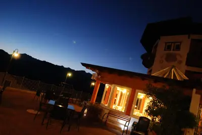 a building with chairs and a table at night at La Montanina Hotel in Val di Non in Malosco