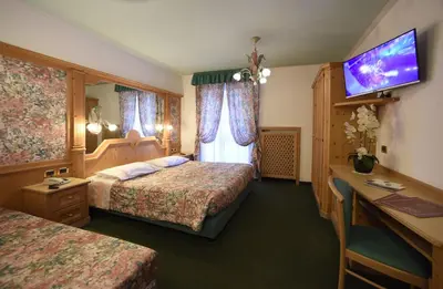 a hotel room with two beds and a television at Hotel Barance in Alleghe