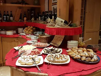 a table with many different types of pastries and bottles of wine at Hotel Barance in Alleghe