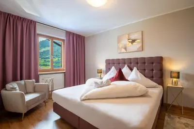 a bedroom with a large bed and a chair at Hotel Residence MaVie in Lagundo