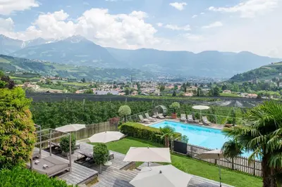 a resort with a pool and mountains in the background at Hotel Residence MaVie in Lagundo