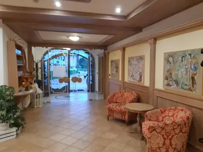 a hallway with two chairs and a table in a building at Hotel El Pilon in Pozza di Fassa