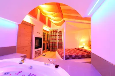 a bathroom with a tub and a bedroom with a bed at Hotel El Pilon in Pozza di Fassa