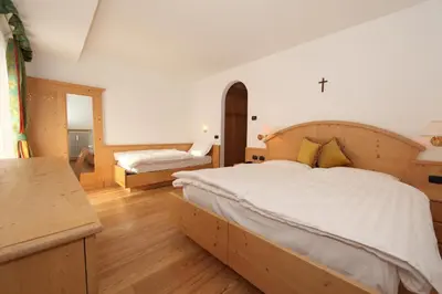 a bedroom with a large bed and a desk at Hotel El Pilon in Pozza di Fassa