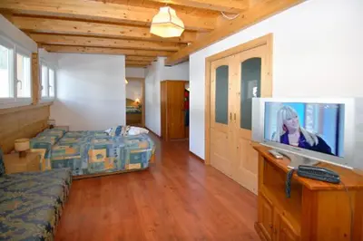 a bedroom with a bed and a flat screen tv at Hotel El Pilon in Pozza di Fassa