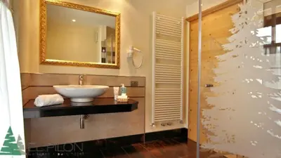 a bathroom with a sink and a mirror and a shower at Hotel El Pilon in Pozza di Fassa