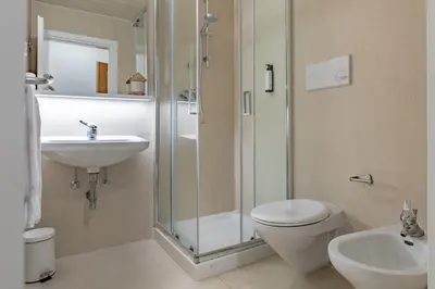 a bathroom with a shower and a toilet and a sink at Hotel Kronplatzer Hof in Rasun di Sopra