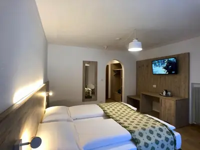 a bedroom with a white bed and a tv on the wall at Hotel Kronplatzer Hof in Rasun di Sopra