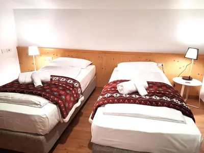a hotel room with two beds and two lamps at Hotel Kronplatzer Hof in Rasun di Sopra