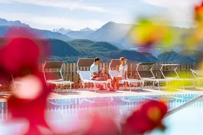 two people sitting in chairs next to a pool at Residence Tannhof in Caldaro