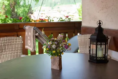 a lantern and a vase of flowers on a table at Residence Lastè in Moena