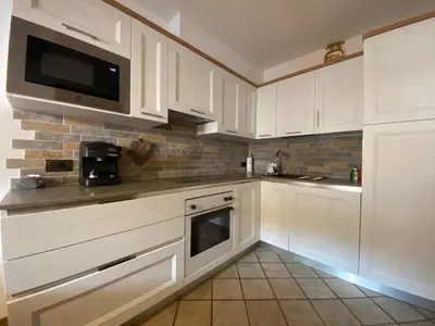 a kitchen with white cabinets and a microwave at Residence Lastè in Moena