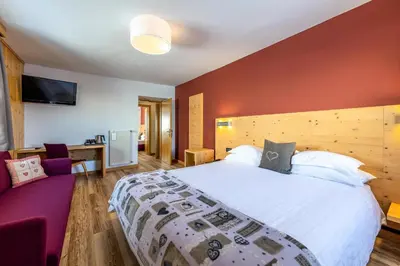 a bedroom with a large bed and a purple couch at Hotel Col di Lana in Canazei