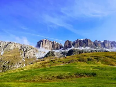 a grassy hill with mountains in the background at Hotel Col di Lana in Canazei