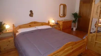 a bedroom with a wooden bed and two night stands at Condominio La Mont 2 in Piaia