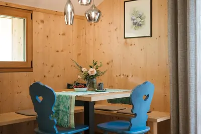 a dining room with a table and two blue chairs at Birkenhof in Marlengo