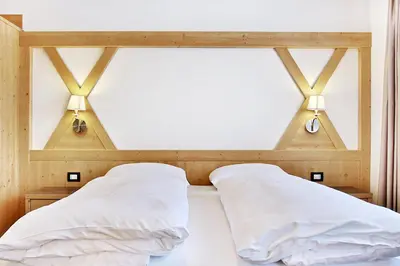 a bed with two white pillows and two lights at B&B La Tranquillitè in Corvara in Badia