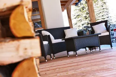 a row of chairs on a deck with a window at B&B La Tranquillitè in Corvara in Badia
