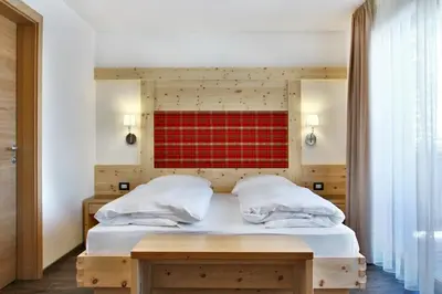 a bedroom with a bed with a red wall at B&B La Tranquillitè in Corvara in Badia
