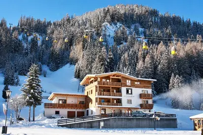 a building in the snow with a ski lift at B&B La Tranquillitè in Corvara in Badia