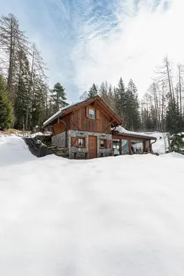 a log cabin with snow in front of it at Cain Comfort Chalet in Fondo