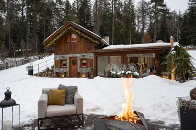 a fireplace in front of a log cabin in the snow at Cain Comfort Chalet in Fondo
