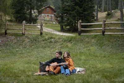 a man and woman sitting on a blanket in the grass at Cain Comfort Chalet in Fondo