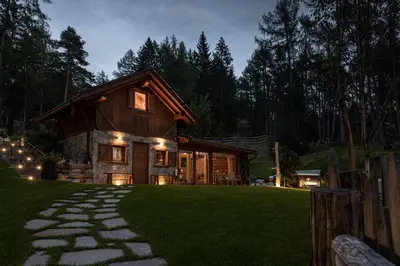 a log cabin with a pathway leading to it at night at Cain Comfort Chalet in Fondo