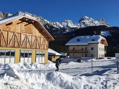 a person standing in the snow in front of a building at Les Pizades in San Cassiano