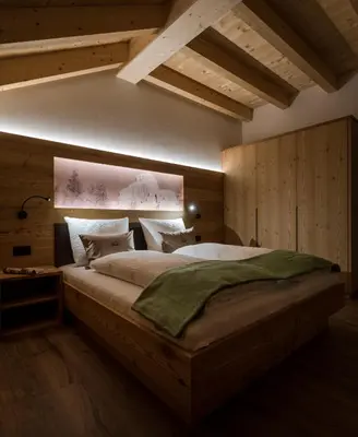 a bedroom with a large bed with wooden walls at Les Pizades in San Cassiano