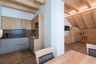 a kitchen with wooden cabinets and a table with chairs at Les Pizades in San Cassiano