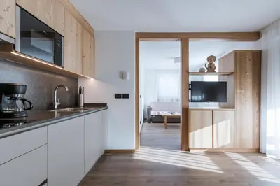 a kitchen with white cabinets and a television at Les Pizades in San Cassiano