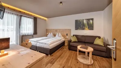 a hotel room with a bed and a couch at Autentis in Rasùn di Sotto