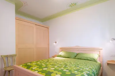 a bedroom with a bed with a green comforter at Villa Edelweiss in Alleghe